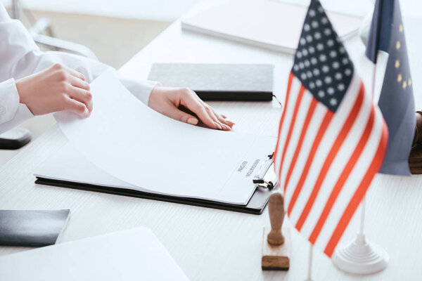 cropped view of woman holding document with immigration reform lettering near american and european flags 