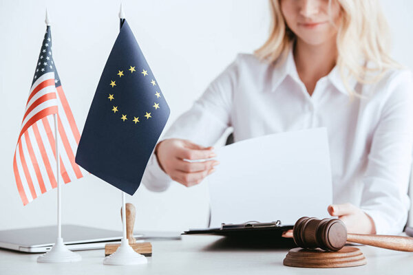 cropped view of woman holding document near american and european flags isolated on white