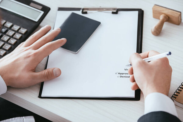 cropped view of man putting check sign on document with approved lettering 