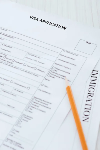 pencil near documents with visa application and immigration lettering