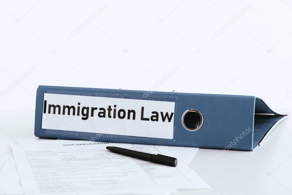 selective focus of folder with immigration law lettering near documents and pen 