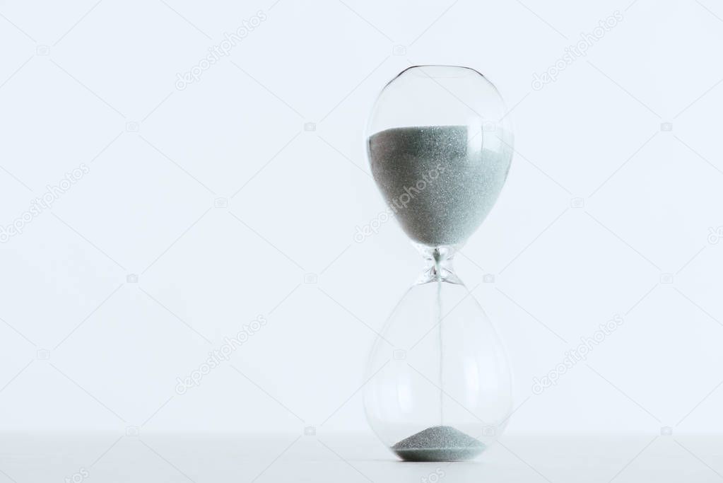 selective focus of running sand in hourglass isolated on white