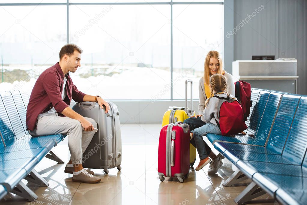 daughter looking at mom while sitting in waiting hall next to dad