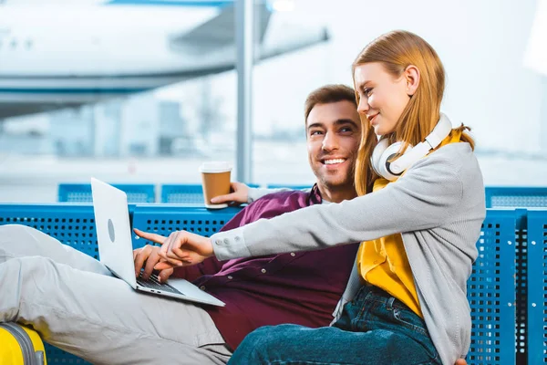 Cheerful Woman Holding Paper Cup While Pointing Finger Laptop Boyfriend — Stock Photo, Image