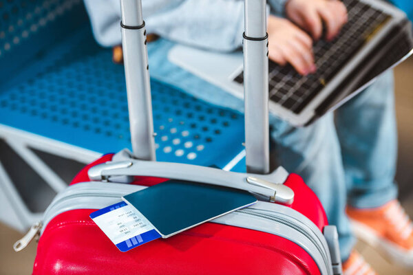 cropped view of luggage with child using laptop on background 