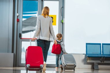 arkadan görünüşü anne ve kızı ile bavul gidiş salonunda yürüyüş