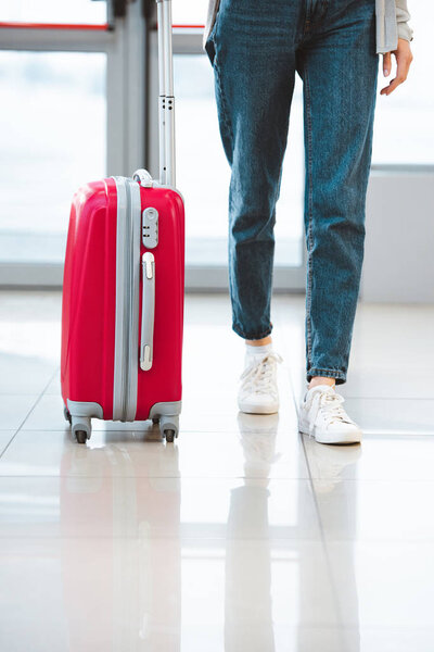 cropped view of woman walking with suitcase in airport 