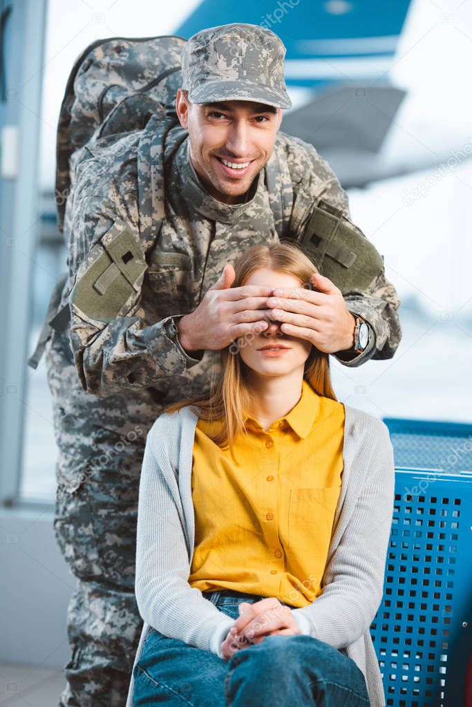 handsome veteran in military uniform closing eyes of girlfriend 