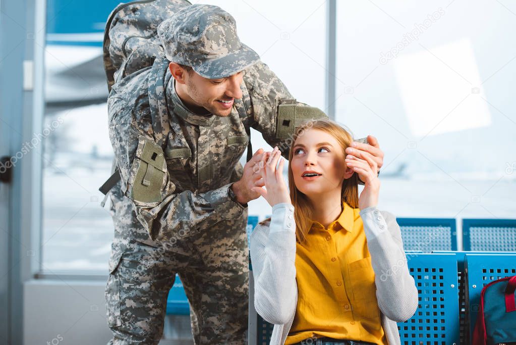 handsome veteran looking at surprised girlfriend in airport 