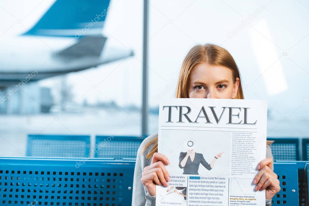 woman holding travel newspaper in waiting hall in airport