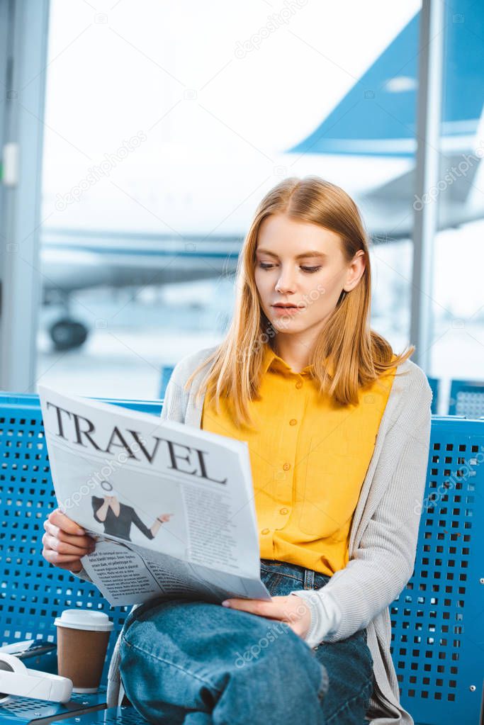 attractive woman reading travel newspaper in departure lounge