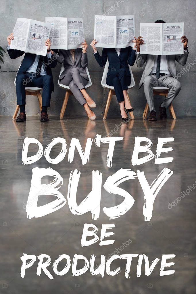 businesspeople sitting on chairs and holding newspapers in front of faces in waiting hall with dont be busy be productive lettering on floor  