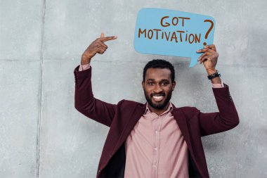 Kameraya bakarak ve konuşma balonu ile parmak ile işaret gülümseyen Afro-Amerikan rahat işadamı motivasyon sorum var.