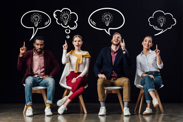 multiethnic group of people sitting on chairs and showing idea gestures with light bulbs icons in speech and thought bubbles above heads isolated on black