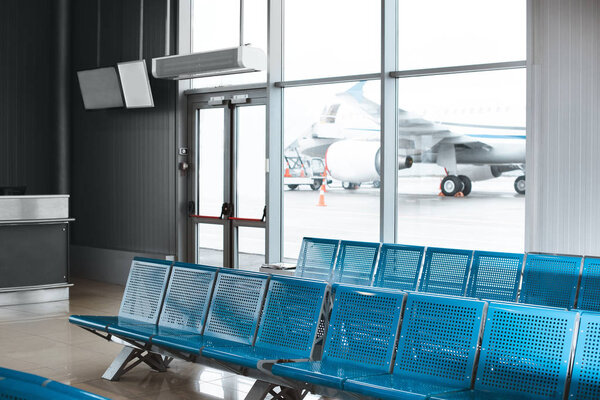 empty waiting hall with blue metallic seats in airport 
