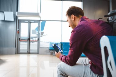 Passport ile uçak bileti tutarak ve kapısı havaalanında yakın oturan gülümseyen adam