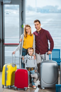 happy family standing with luggage in departure lounge clipart