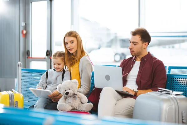 デジタル タブレットの空港でラップトップを使用している父 母の近くを見てかわいい子供 — ストック写真