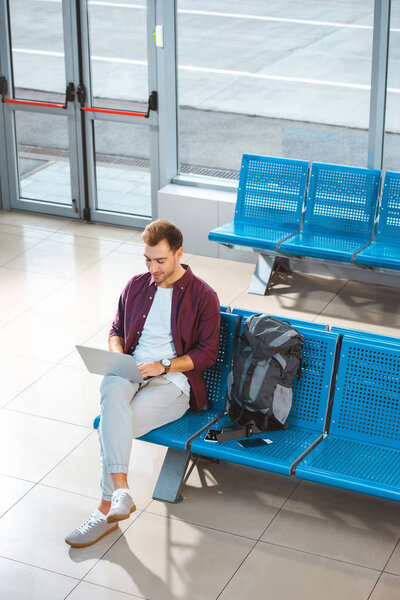 overhead view of handsome man using laptop while sitting in waiting hall