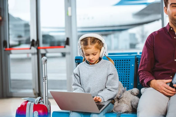 Bedårande Barn Hörlurar Använder Laptop Nära Pappa Väntan Hall — Stockfoto