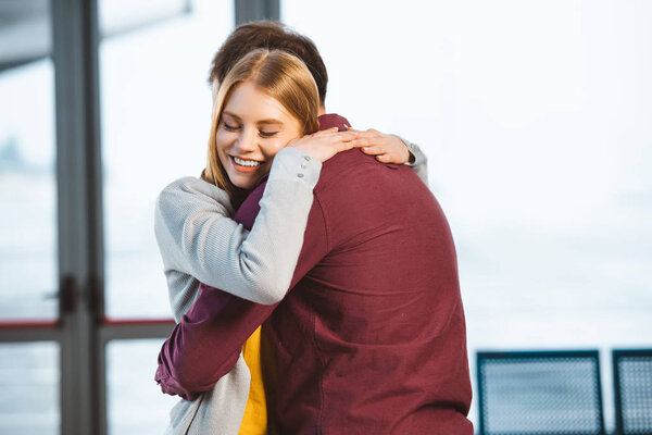 attractive woman smiling with closed eyes while hugging boyfriend