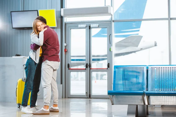 Cheerful Woman Hugging Boyfriend Waiting Hall Suitcase — Stock Photo, Image