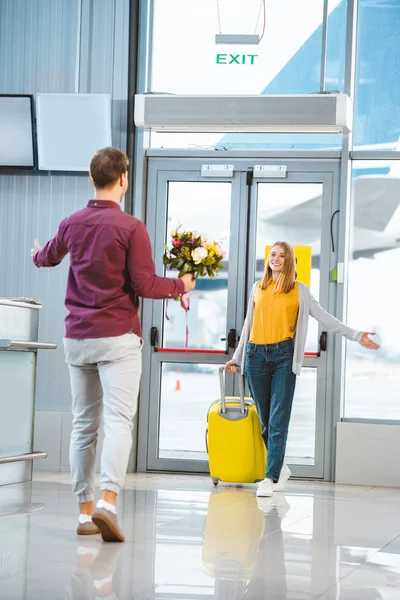 Baksidan Pojkvän Med Blommor Möte Vackra Flickvän Med Resväska Flygplats — Stockfoto