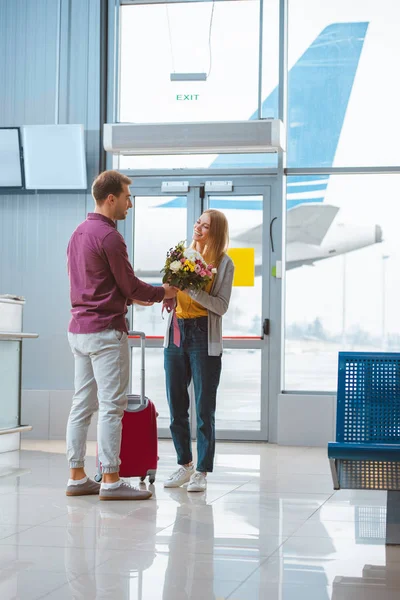 Fröhlicher Freund Schenkt Freundin Flughafen Blumen — Stockfoto