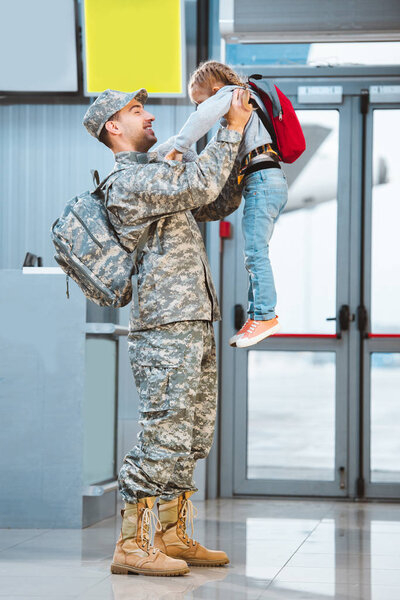 happy father in military uniform holding in arms cute daughter in airport 