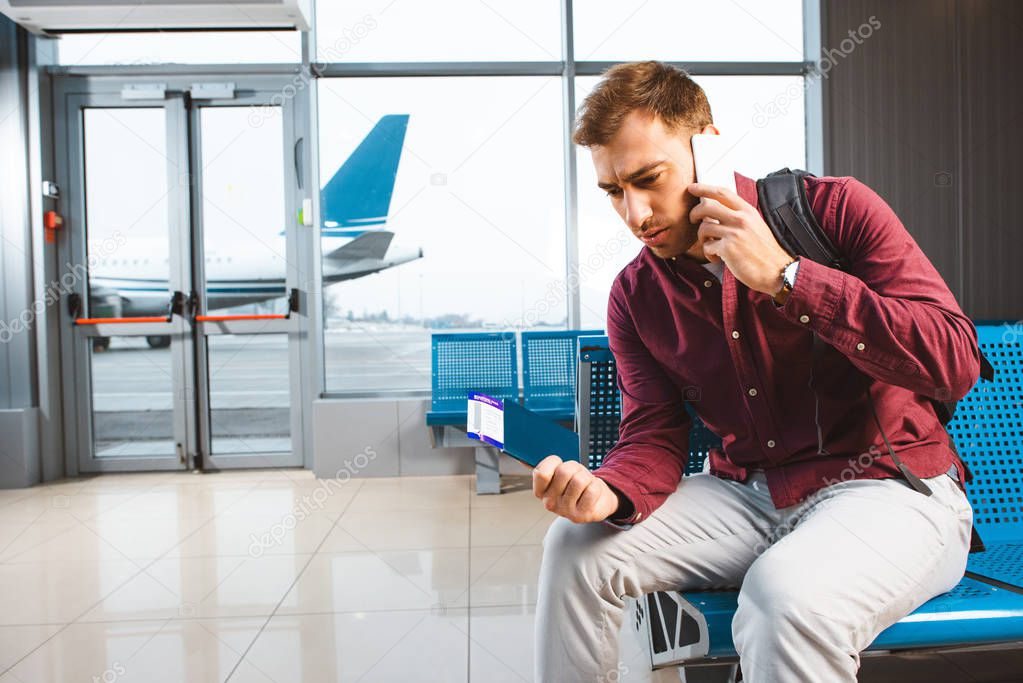man talking on smartphone while sitting in waiting hall 