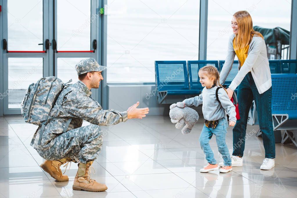 cheerful daughter running to happy father in military uniform in airport 