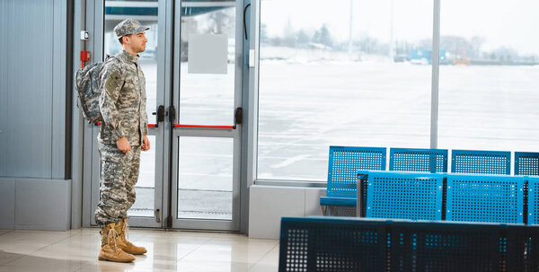 veteran in military uniform standing with backpack in departure lounge