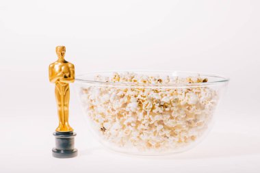 KYIV, UKRAINE - JANUARY 10, 2019: shiny oscar award with popcorn bowl on white background clipart