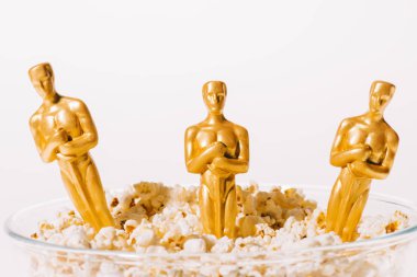 KYIV, UKRAINE - 10 HAZİRAN 2019: Hollywood Oskar ödülü heykelleri beyaz üzerine izole edilmiş patlamış mısır kasesinde 