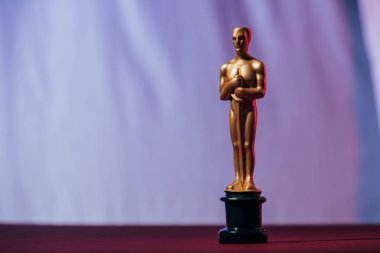 KYIV, UKRAINE - JANUARY 10, 2019: golden oscar award on purple background with copy space clipart