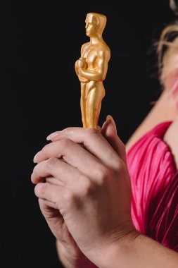 KYIV, UKRAINE - JANUARY 10, 2019: close up of woman in pink holding oscar award isolated on black clipart
