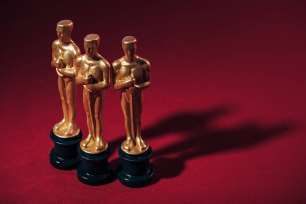 КИЕВ, УКРАИНА - 10 ЯНВАРЯ 2019 года: выборочная фокусировка статуэток Золотого Оскара на красном фоне с копировальным пространством