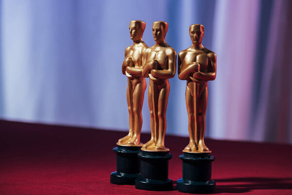 KYIV, UKRAINE - JANUARY 10, 2019: selective focus of golden oscar award statuettes with purple background