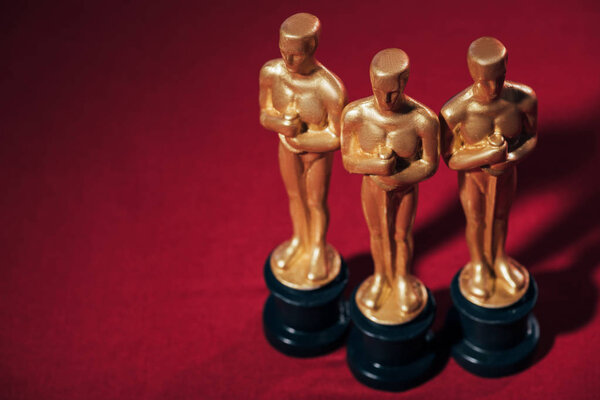KYIV, UKRAINE - JANUARY 10, 2019: selective focus of golden oscar award statuettes on red background with copy space