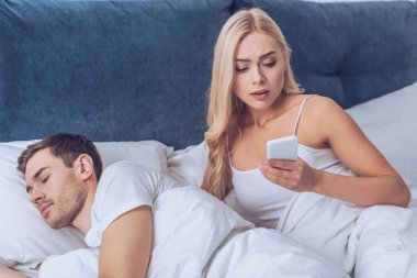kıskanç karı koca yatakta, güvensizlik kavramı uyku sırasında Smartphone kullanarak