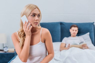 Smartphone ile konuşmak ve uzakta iken kocası yatakta kitap okumak arıyorum genç kadın 