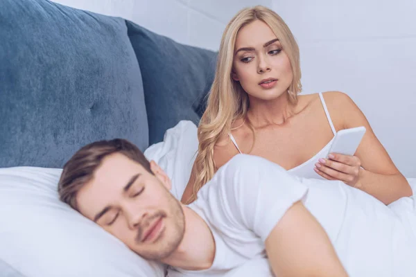 Jaloerse Vrouw Smartphone Houden Kijken Naar Man Slapen Bed Wantrouwen — Stockfoto