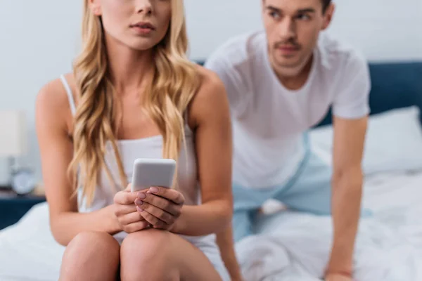 Tiro Cortado Mulher Jovem Usando Smartphone Enquanto Marido Ciumento Espreitando — Fotografia de Stock