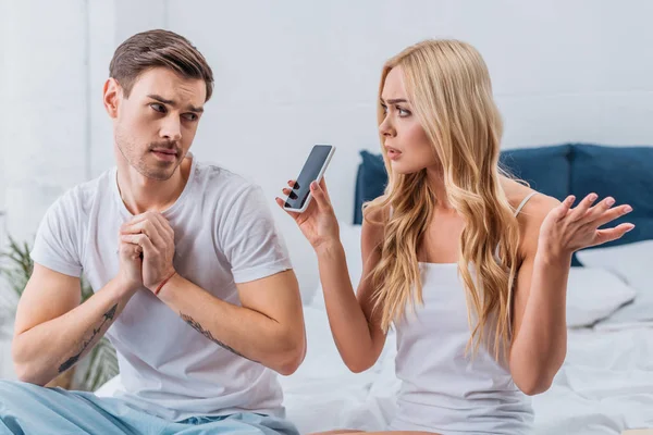 Confused Woman Showing Smartphone Suspicious Boyfriend Bedroom — Stock Photo, Image