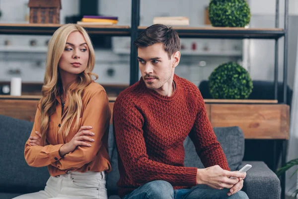 Young Man Holding Smartphone Looking Confident Girlfriend Sitting Crossed Arms — Stock Photo, Image