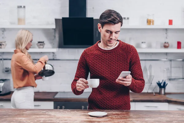 Young Man Holding Cup Using Smartphone Kitchen Relationship Problem Concept — Stock Photo, Image