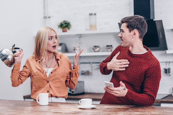 эмоциональная молодая пара ссорящаяся на кухне, концепция недоверия
