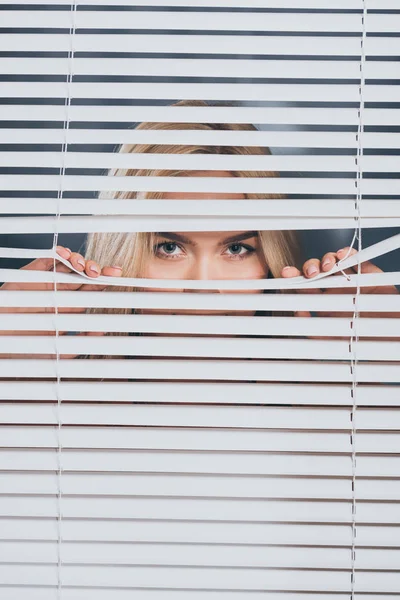 Jonge Vrouw Kijken Camera Gluren Door Blinds Wantrouwen Concept — Stockfoto