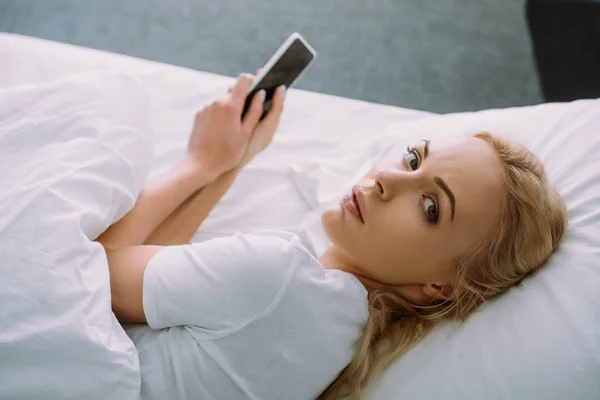Sad Woman Looking Camera Using Smartphone Bed Home — Stock Photo, Image