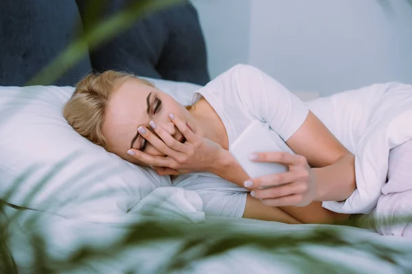 Mulher Estressada Deitada Cama Cobrindo Rosto Com Mão Usando Smartphone — Fotografia de Stock